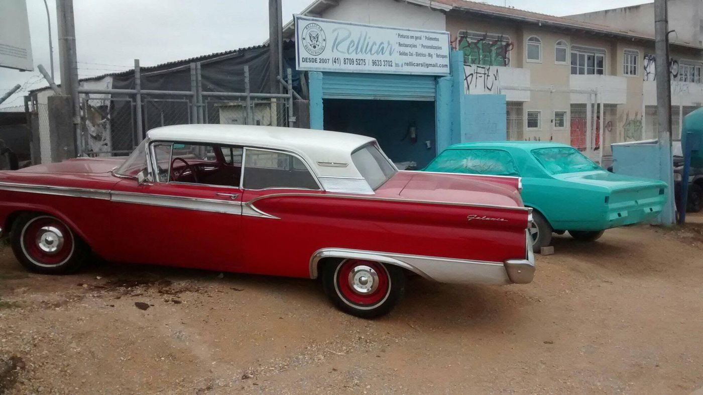 Ford Galaxie vermelho e branco ao lado de um Opala em restauração
